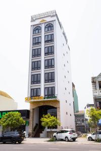 a tall white building with a sign on it at SeaColor Beachstay Danang Hotel by Haviland in Da Nang