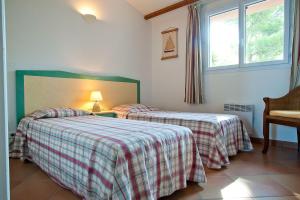 a bedroom with two beds and a window at Les Hauts de Pavellone in Porto-Vecchio