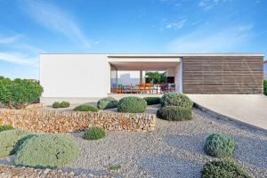 a backyard with a stone retaining wall and a house at Villa Tamarells Ullastres in Punta Prima