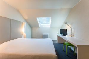 um quarto com uma cama e uma secretária com uma televisão em Campanile Rouen Sud - Zénith - Parc Expo em Saint-Étienne-du-Rouvray