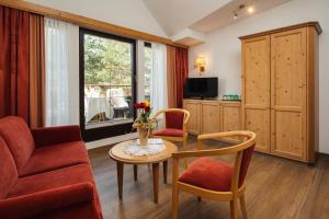 een woonkamer met een tafel en stoelen en een televisie bij Hotel Garni Alpenruh-Micheluzzi in Serfaus