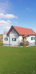 a white house with a red roof and a green field at Franz Josef am Ratschenberg in Eisenberg an der Pinka