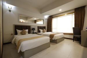 a hotel room with two beds and a window at Aristocrat Hotel in Kolkata