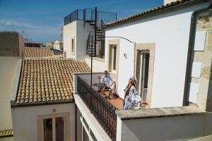 zwei Personen stehen auf einem Balkon eines Gebäudes in der Unterkunft Lanterne Magiche Ortigia in Syrakus
