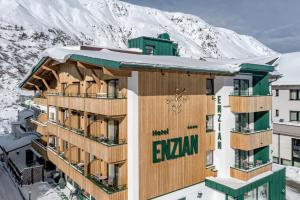 budynek z pokrytymi śniegiem górami w tle w obiekcie Hotel Enzian & Apartmenthotel Johannes w mieście Obergurgl