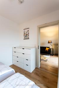 a bedroom with a white dresser and a living room at FESTWIESE - modernes Apartment nahe Neustadter Innenstadt in Neustadt an der Weinstraße