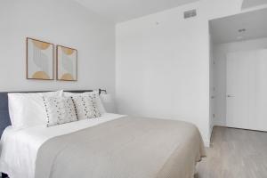 a white bedroom with a white bed with two paintings on the wall at Downtown 1BR w Pool Jacuzzi Gym nr 110 LAX-836 in Los Angeles +49 photos