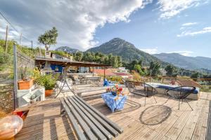a wooden deck with chairs and a table and mountains at Magical view, Villa Asproneri, Kamena Vourla in Kamena Vourla
