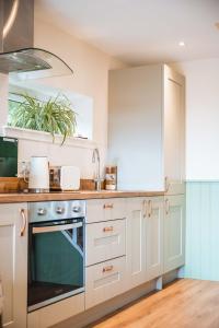 a kitchen with white cabinets and a sink at Taighsona Bothy, Speyside - amazing views! in Archiestown