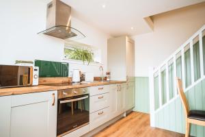 a kitchen with white cabinets and a microwave at Taighsona Bothy, Speyside - amazing views! in Archiestown