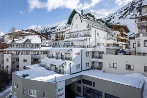 eine Gruppe von Gebäuden mit Schnee auf den Dächern in der Unterkunft Hotel Enzian & Apartmenthotel Johannes in Obergurgl