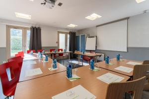 uma sala de conferências com uma mesa longa e cadeiras em Campanile Rouen Sud - Zénith - Parc Expo em Saint-Étienne-du-Rouvray