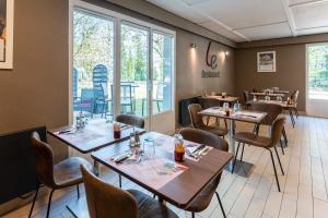 una sala da pranzo con tavoli, sedie e finestre di Campanile Rouen Sud - Zénith - Parc Expo a Saint-Étienne-du-Rouvray