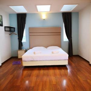 a bedroom with a bed with white sheets and wood floors at Dear Dino Villa Cameron Highlands in Cameron Highlands