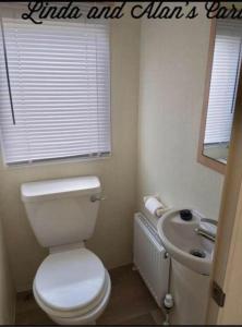 a bathroom with a toilet and a sink and a window at Linda/Alan's Happy Holiday Home in Rhyl
