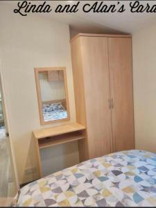 a bedroom with a bed and a mirror and a cabinet at Linda/Alan's Happy Holiday Home in Rhyl