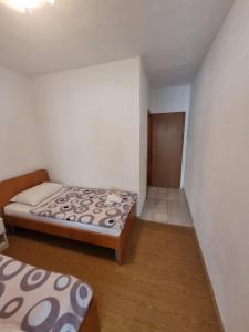 a small bedroom with two beds and a door at Međugorje Apartman Jurković in Donja Mahala