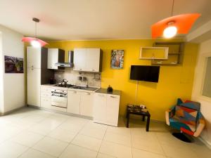 a kitchen with white cabinets and a yellow wall at Ferrari Holiday House - Casa Vacanza nel cuore di Campobasso in Campobasso