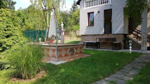 une maison avec une cour dotée d'une fontaine et d'un parasol dans l'établissement Hill View Holiday House nearby Budapest with AC & Pool, à Pilisszentiván