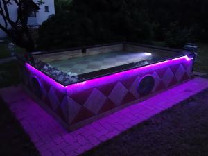 uma banheira de hidromassagem iluminada por luzes roxas em Hill View Holiday House nearby Budapest with AC & Pool em Pilisszentiván