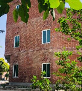 a red brick building with four windows on it at Hosteller - Hostel & Hotel Johar Town Lahore in Lahore