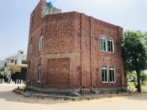 a red brick building with windows on the side of it at Hosteller - Hostel & Hotel Johar Town Lahore in Lahore