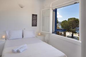 a white bedroom with a bed and a window at Konstantinos and Eleni's Apartment in Koundouros