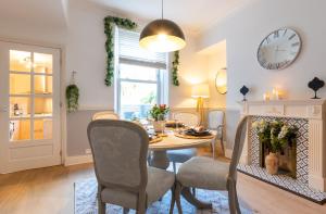 a dining room with a table and chairs and a clock at Beautiful 3 Bedroom Townhouse in Harrogate
