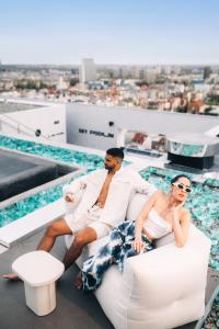 a man and woman sitting on chairs next to a swimming pool at Maistra City Vibes Zonar Zagreb in Zagreb