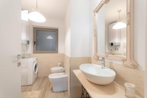 een badkamer met een wastafel, een toilet en een spiegel bij Casa vacanze Montebello in Trieste