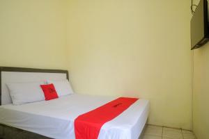 a room with a bed with a red blanket on it at RedDoorz Syariah near RS Permata Medika Ngaliyan Semarang in Tambakaji