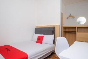 a small room with a bed and a chair at RedDoorz Syariah near RS Permata Medika Ngaliyan Semarang in Tambakaji