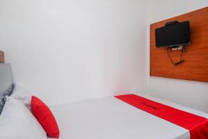 a bedroom with a bed with a tv on the wall at RedDoorz Syariah near RS Permata Medika Ngaliyan Semarang in Tambakaji