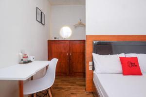 a bedroom with a bed and a desk and a table at RedDoorz near RS Permata Medika Ngaliyan Semarang in Tambakaji +23 photos