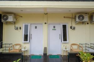 a house with two white doors and two chairs at RedDoorz Syariah near RS Permata Medika Ngaliyan Semarang in Tambakaji