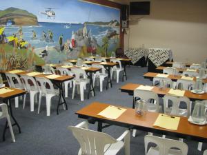 una classe con tavoli, sedie e un grande murale di Kob Inn Beach Resort a Qora Mouth