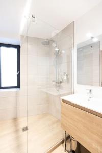 een witte badkamer met een douche en een wastafel bij Bliss - Résidence Hestia in Saint-Étienne
