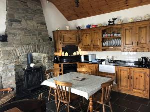 a kitchen with a table and a stone fireplace at Rose Cottage in Greencastle