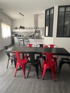 une grande table à manger avec des chaises rouges dans la cuisine dans l'établissement Casa Oliva -situé au 2ème étage sans ascenseur, à Perpignan