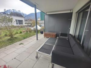 eine abgeschirmte Veranda mit einer Couch auf einer Terrasse in der Unterkunft FeWo Interlaken in Interlaken