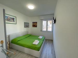 a bedroom with a green bed and a window at Baja Moderno Trilocale vicino al mare in Bibione