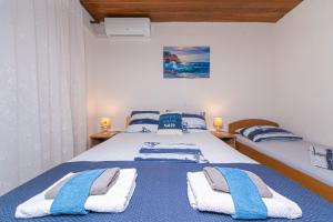 ein Schlafzimmer mit einem blauen und weißen Bett mit Handtüchern darauf in der Unterkunft Apartmani Jakiruša in Brela