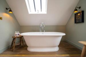 uma banheira branca na casa de banho com uma clarabóia em The Bottle & Glass Inn - Book All 3 Rooms em Henley on Thames