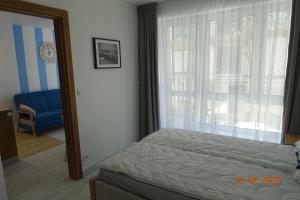 a bedroom with a bed and a window and a chair at APARTAMENT PRZY PLAŻY 2 in Rowy