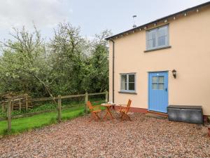 dom z niebieskimi drzwiami oraz stołem i krzesłami w obiekcie Plum Cottage w mieście Colebrooke