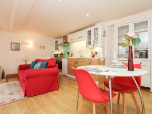 a kitchen and living room with a table and red chairs at Plum Cottage in Colebrooke