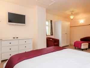 a bedroom with a bed and a tv on the wall at Plum Cottage in Colebrooke