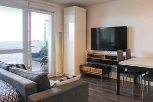 een woonkamer met een televisie en een tafel met een bank bij Brand new studio with an open view on Paris in Arcueil