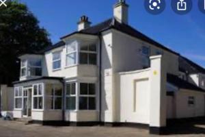 a large white house with a lot of windows at SeaBright; one bed apartment with garden and parking in Mundesley
