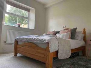 a bedroom with a wooden bed with pillows and a window at SeaBright; one bed apartment with garden and parking in Mundesley